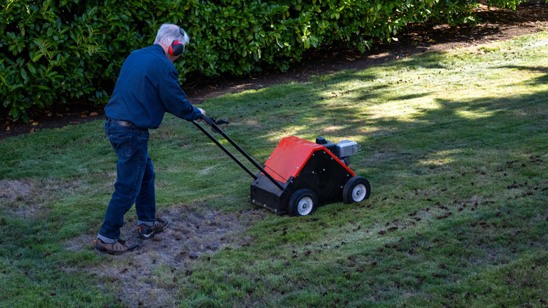 Man aerating lawn with core aerator