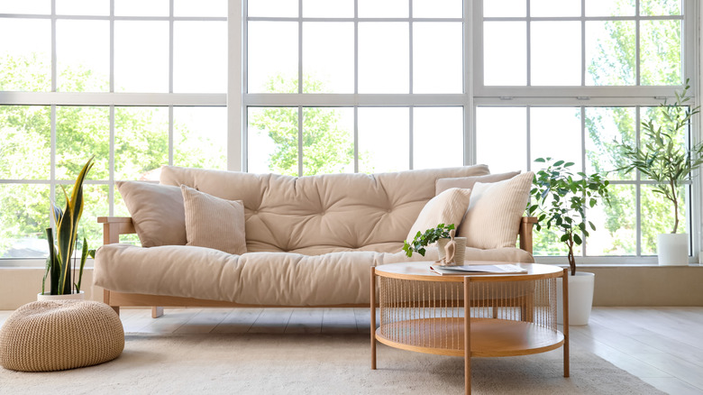 Living room with plain tan couch in front of large window