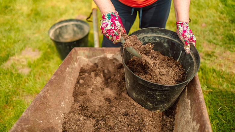 Woman filling a planter pot with topsoil