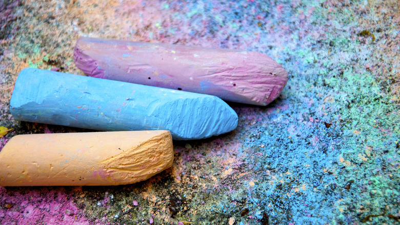 Three pieces of chalk on top of colorful sidewalk