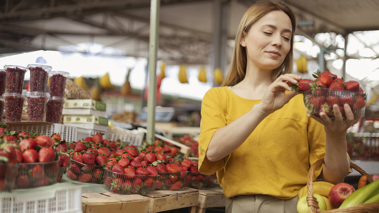 woman picking strawberries in store