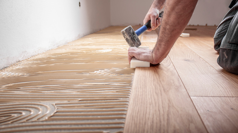 person laying wood flooring