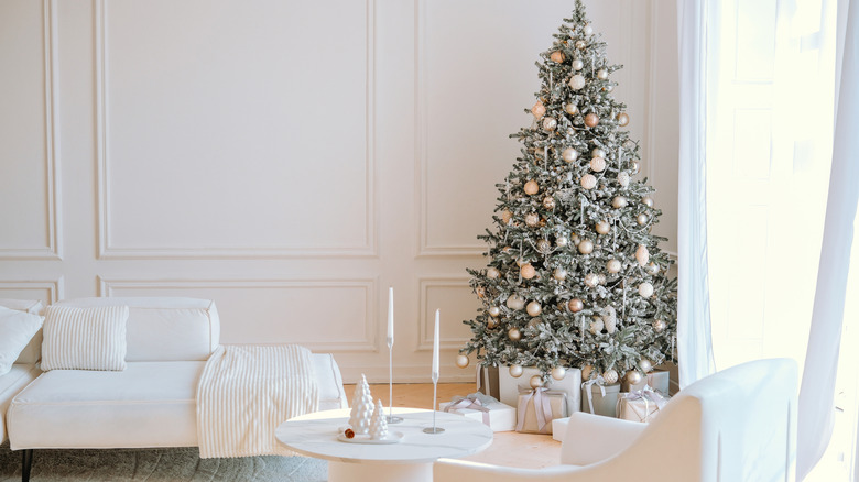 All white minimalist living room decorated with a Christmas tree in corner
