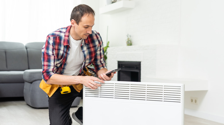 A person holding a radiator removed from its mounting