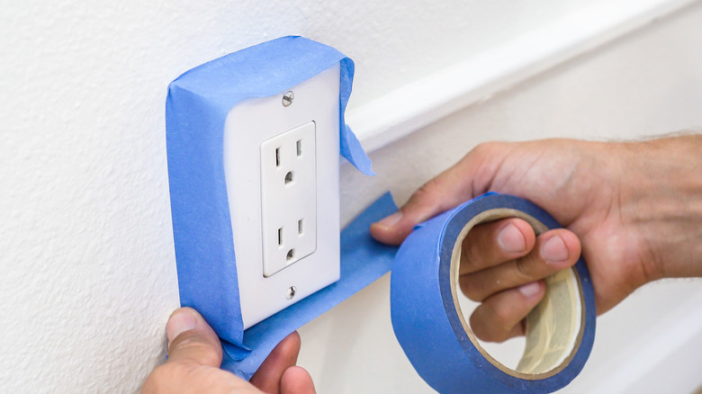 Man taping electrical wall outlet