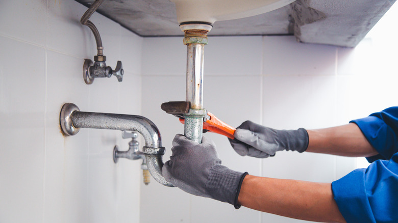 Close up of plumber using wrench to unscrew water pipes