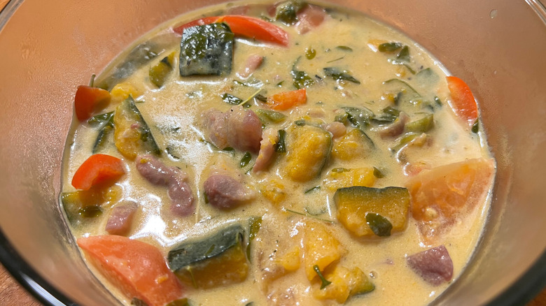 A close-up of a vegetable soup stored in a glass container
