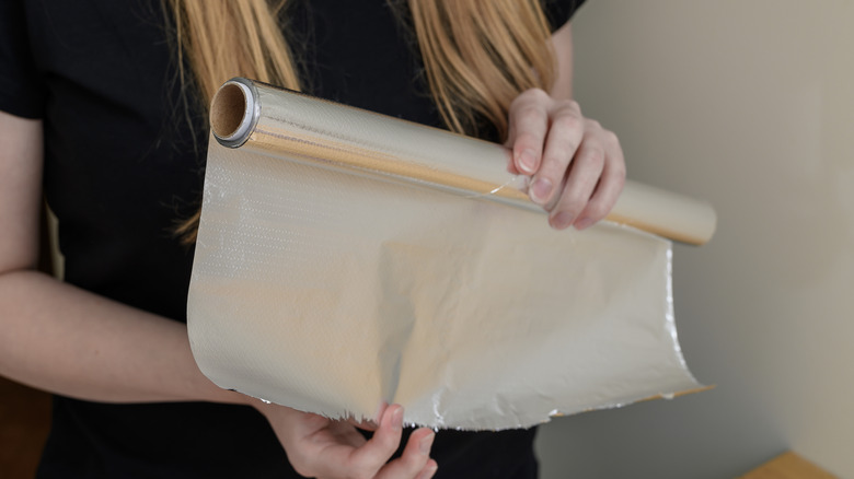 Woman unrolling aluminum foil