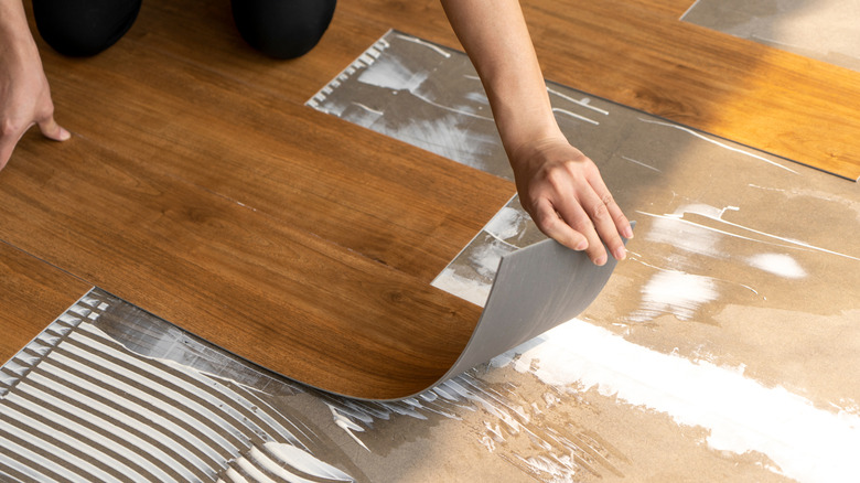 A woman installs glue-down vinyl flooring