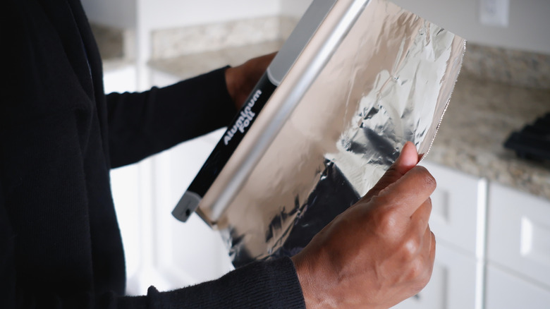 Close up of person unrolling aluminum foil