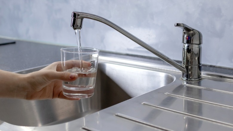 Person filling glass from kitchen tap