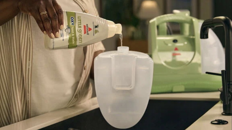 A woman pours Bissell's cleaning solution into the Bissell Little Green Cleaner