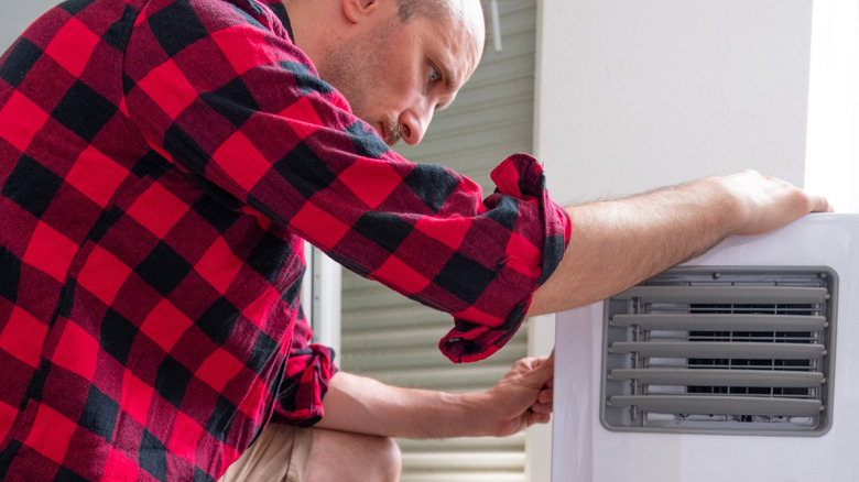 Man examining a portable air conditioner unit