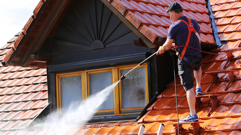 person power washing windows from roof