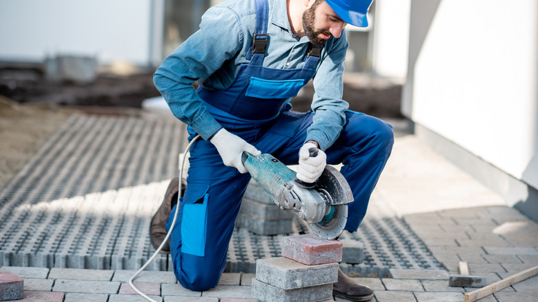 Someone using a tile saw to cut pavers
