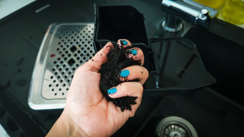 A person holding old coffee grounds for cleaning
