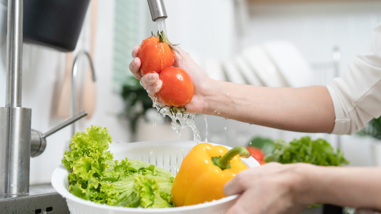 Washing vegetables under running water in kitchen sink