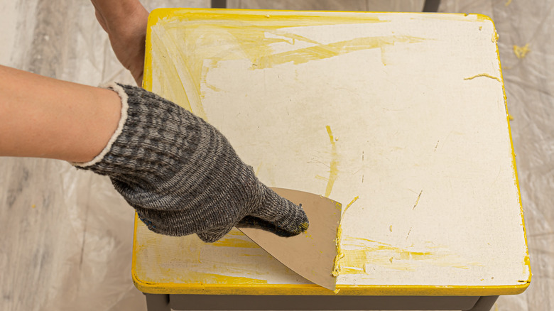 Hand scraping paint off table