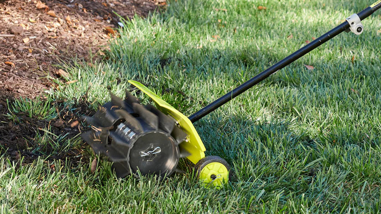 Ryobi Expand-It rubber broom attachment powered in a green lawn