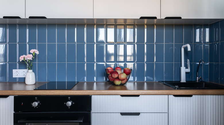 kitchen with white cabinets, blue tile backsplash, and wooded countertop