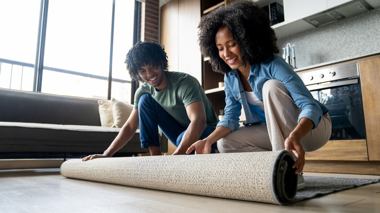 Two people rolling up an area rug
