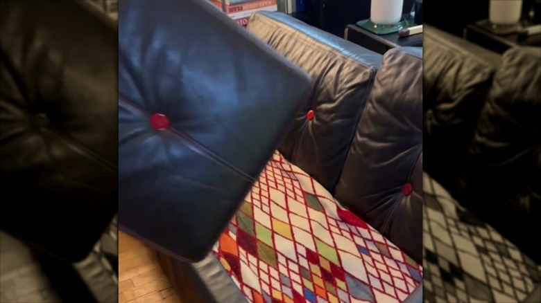 A woman storing a rug under the sofa cushions