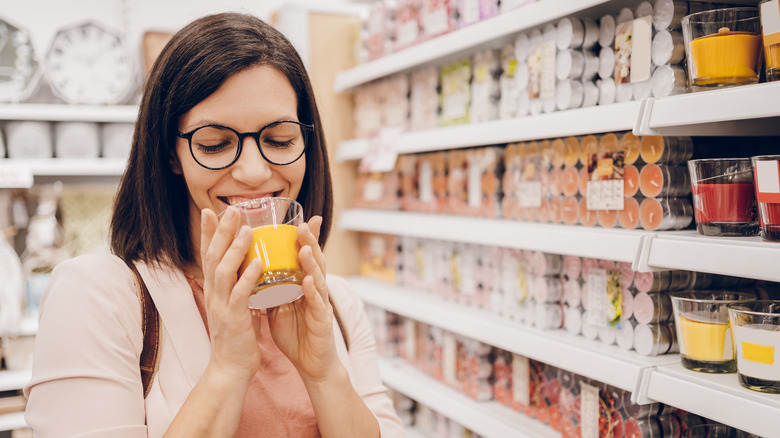 person smelling a candle in a store