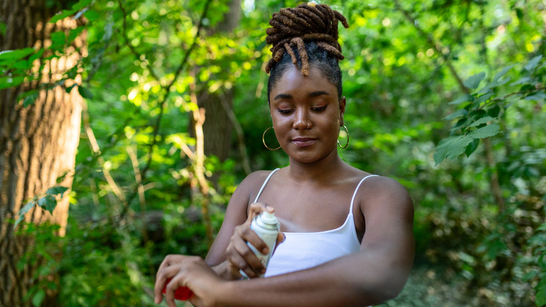Woman applying insect repellent spray.