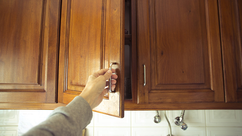 Person opening orange colored dated kitchen cabinet