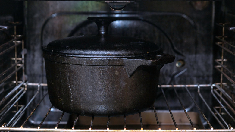 A cast iron Dutch oven with lid inside an oven