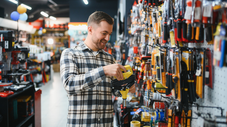 A smiling man is looking at power tools in a hardware store