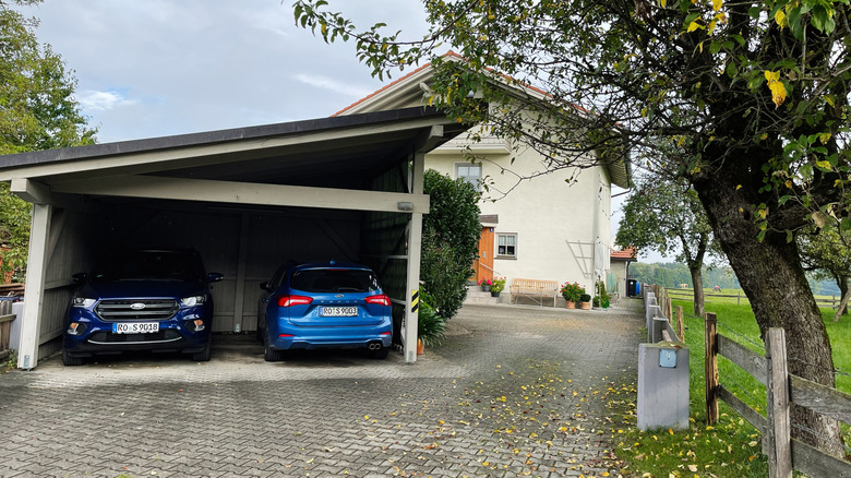 Two blue cars side by side in a carport with a sloped roof