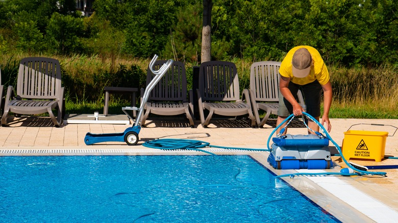 A person uses a cleaning machine on a swimming pool