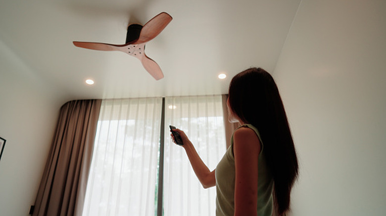A woman turning on her ceiling fan