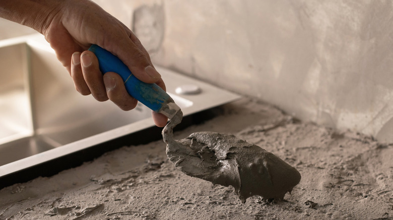 Person covers countertop with cement plaster.