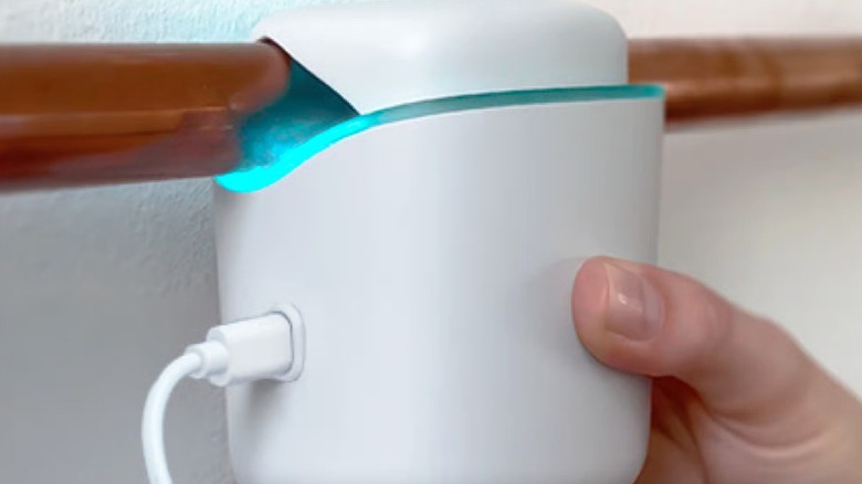 A hand installs the Droplet smart home water sensor to a water supply pipe.