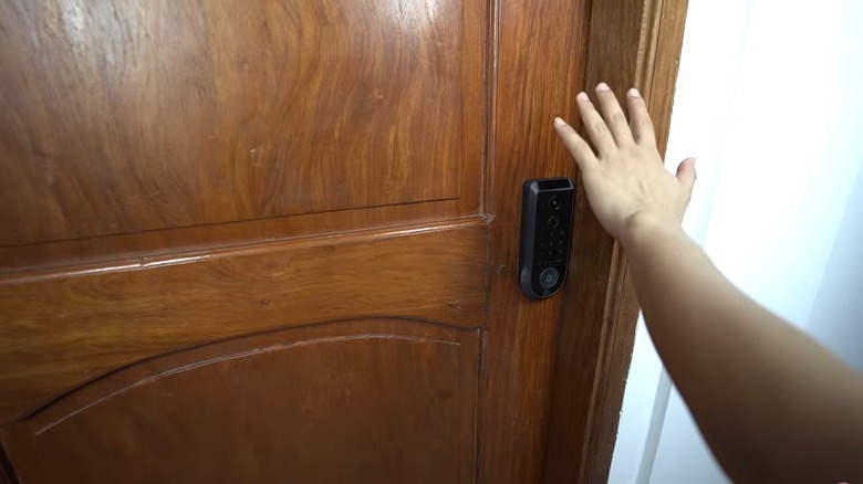 A hand waves over a smart lock to open a door.