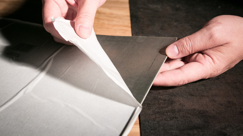 Person peeling adhesive tile