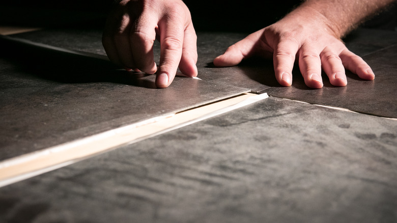 Person installing adhesive tile