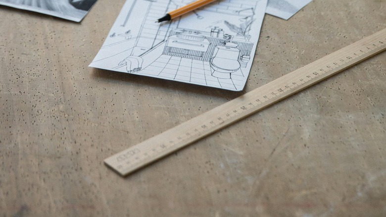 Yardstick, pen, and sketches on table