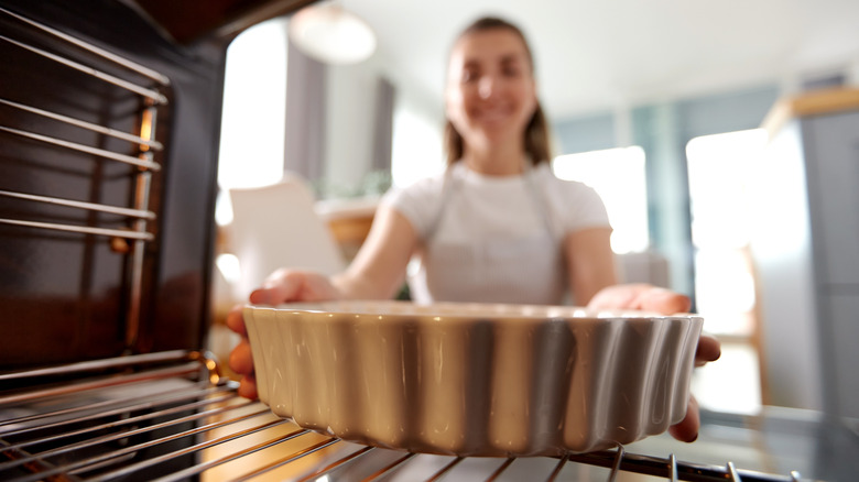 person putting cookware into oven