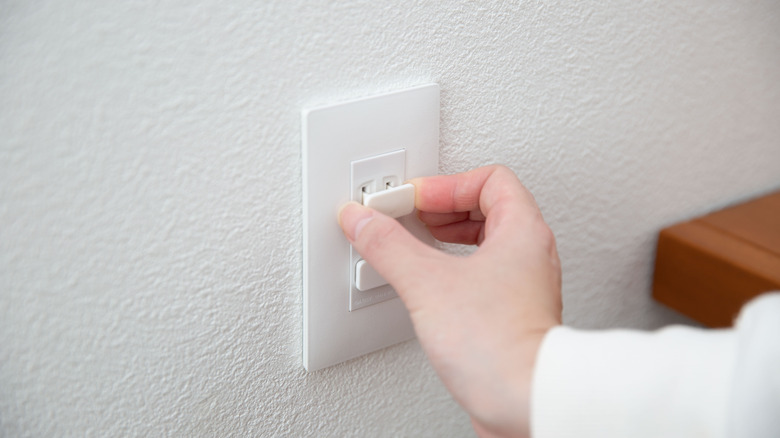 hand covering a plug with plain plastic covers