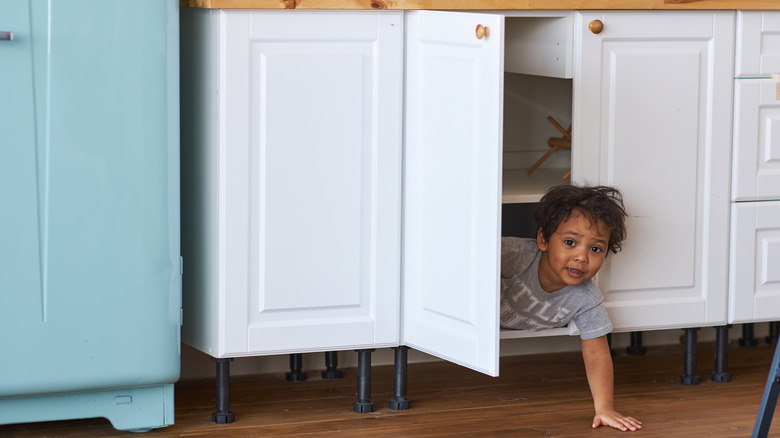 Child coming out of cabinet