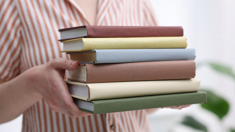 woman holds up a stack of books