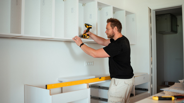 A man installing pre-fab cabinets in the kitchen.