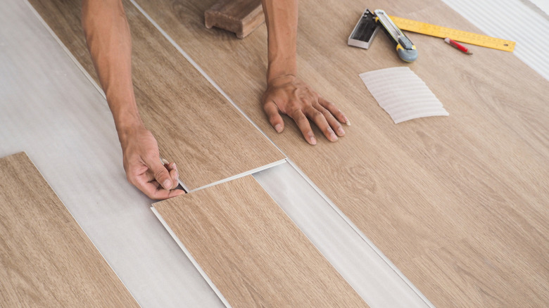 A technician lying down luxury vinyl flooring tiles.