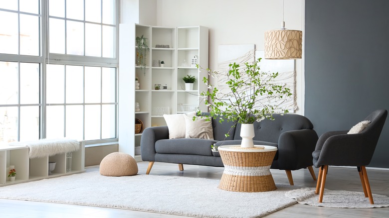 Blooming branches with vase on coffee table in interior of living room