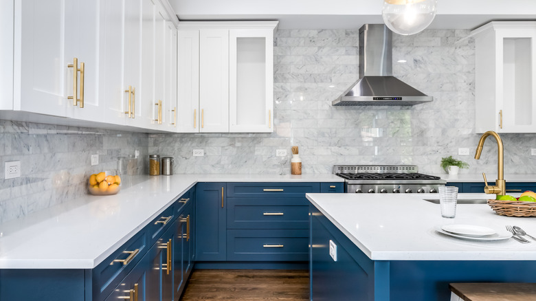 Luxurious kitchen space with dark blue lower cabinets and kitchen island, and white upper cabinets