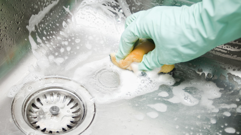 someone cleaning the sink with sponge