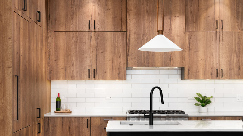 Modern kitchen with woods cabinets, tile backsplash, and a stone island.